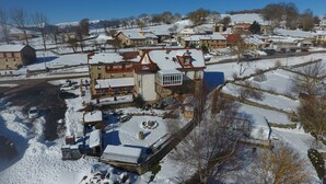 A snow-covered village with traditional buildings, a central square with a fountain, and a clear blue sky. - Pensión El Carloto (Campoo de Yuso)