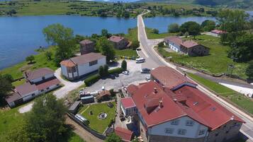 Un village au bord d’un lac, avec des bâtiments traditionnels en pierre, une rue principale et un pont enjambant le lac.