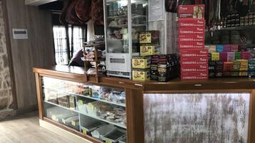 Een bakkerij met een vitrine vol gebak en planken met verpakte producten.
