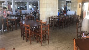 A spacious restaurant with wooden tables and chairs, a stone pillar, and a bar area in the background. - Pensión El Carloto (Campoo de Yuso)