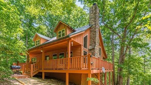 A log cabin with a balcony, a chimney, and a deck.