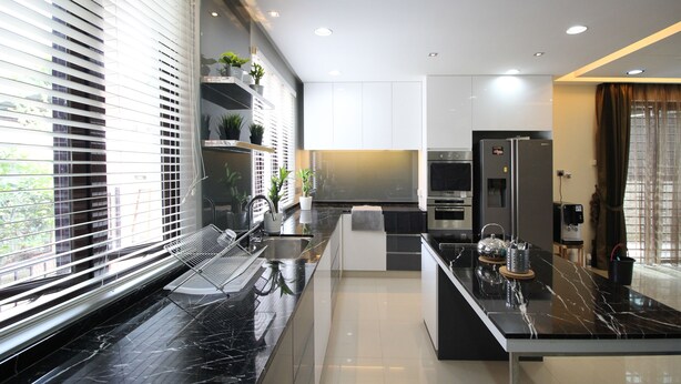 A modern kitchen with black marble countertops, stainless steel appliances, and a built-in island.