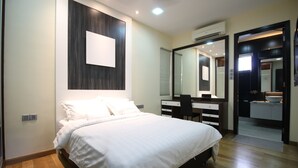 A modern bedroom with a large bed, a vanity with a mirror, and a walk-in closet.