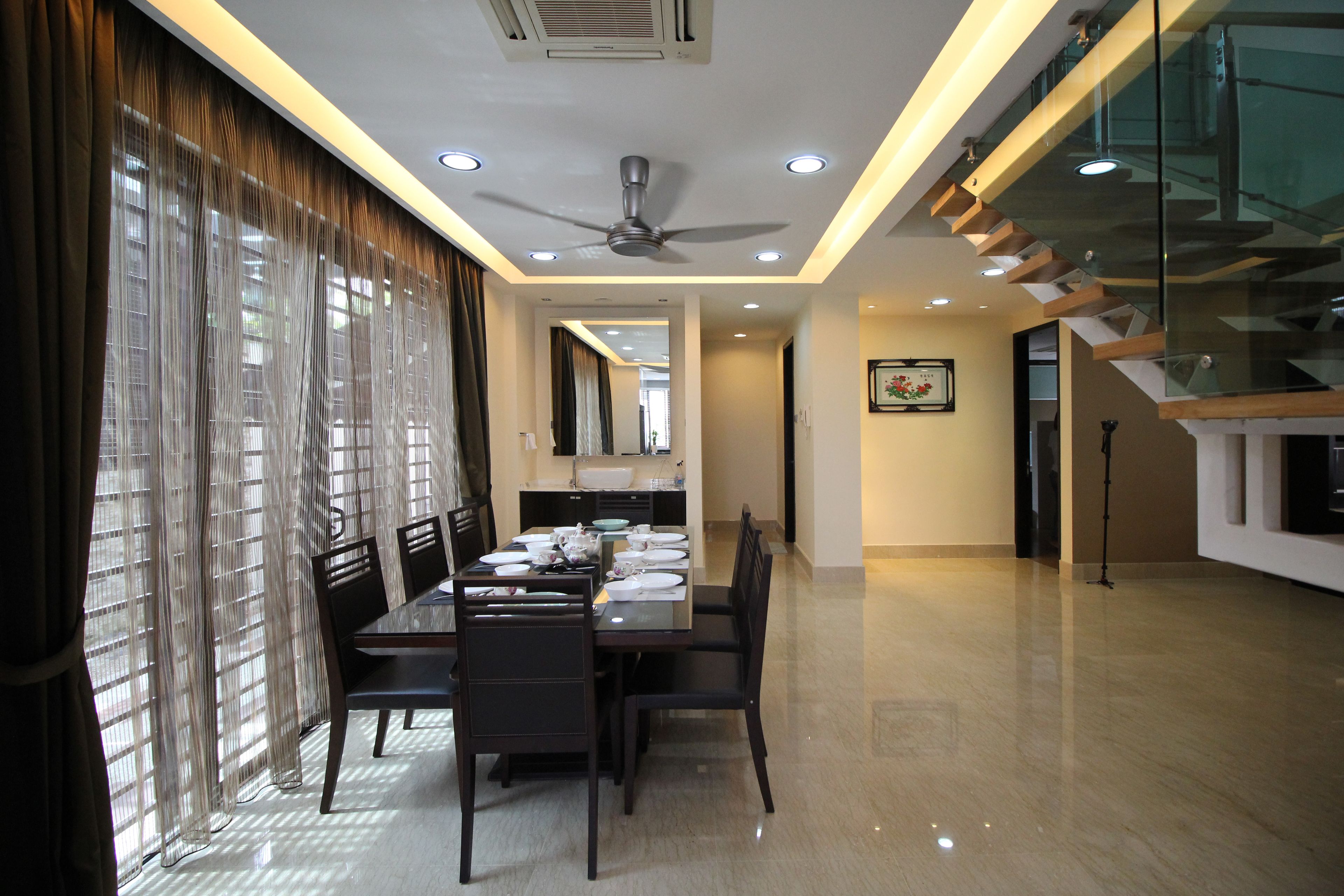 A dining area with a table set for four, a ceiling fan, and a staircase leading to an upper level.