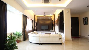 A modern living room with a curved sofa, a flat-screen TV, and potted plants.