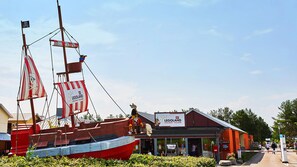 Un velero rojo y blanco con bandera de calavera y huesos cruzados, atracado frente a un edificio que dice "LEGOLAND Holiday Village".