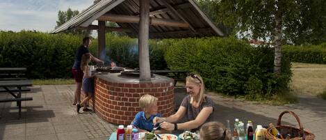 A picnic setup with a table, food, and a brick oven.