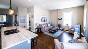 A modern living room with a kitchen island, a sofa, a coffee table, and a TV. - Oceanfront oasis located in historical Annapolis Royal.  (Annapolis Royal)
