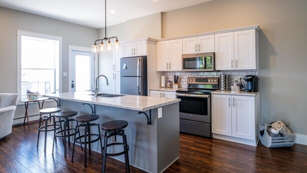 A modern kitchen with a central island, bar stools, stainless steel appliances, and white cabinetry. - Oceanfront oasis located in historical Annapolis Royal.  (Annapolis Royal)