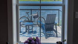 A room with a large window overlooking a lake and greenery, a bicycle, a chair, and a small table with a vase of flowers. - Oceanfront oasis located in historical Annapolis Royal.  (Annapolis Royal)