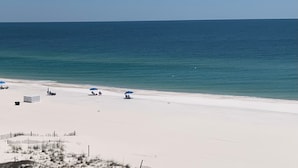 A beach with white sand and a clear blue ocean. There are several umbrellas and beach chairs. - Simply Irresistible 2 *Gulf Front View*Make A Reservation For Fun At The Beach! (Orange Beach)
