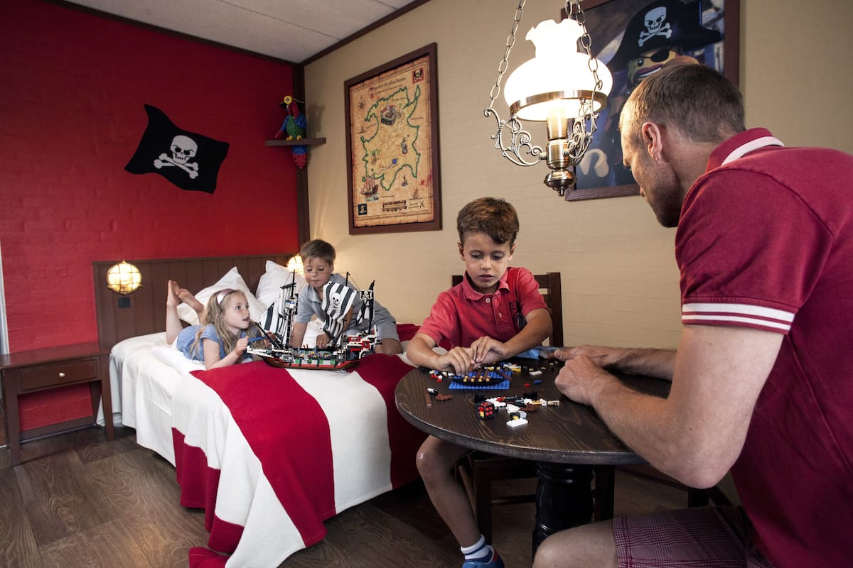 A room with a bed, a table with toys, and a map on the wall.