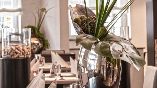 A reception desk with a large, reflective vase containing a plant and decorative elements. - Hotel Concordia (Euskirchen)