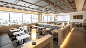 Un café moderno con mesas y bancos de madera, amplias ventanas y vistas a la ciudad.