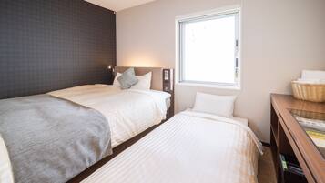 A hotel room with two beds, a window, a nightstand, and a wall-mounted lamp.