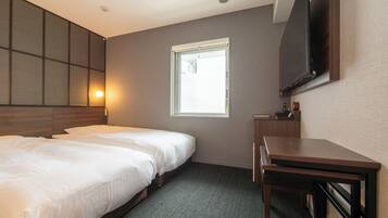 A hotel room with two beds, a desk, a TV, and a window with a view.