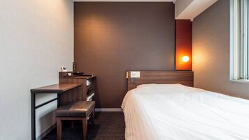 A hotel room with a bed, a desk, a chair, and a nightstand.