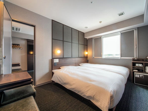 A hotel room with a bed, a desk, a chair, a wardrobe, and a window.