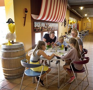 A family dining at a restaurant with a nautical theme, including a barrel and a ship painting. - LEGOLAND Wild West Cabins (Billund)