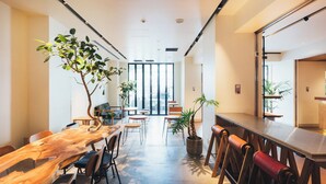 Un interior moderno con una larga mesa de madera, varias sillas y plantas en macetas.