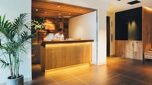 Un área de recepción con mostrador de madera, plantas en macetas y una decoración de estilo moderno.