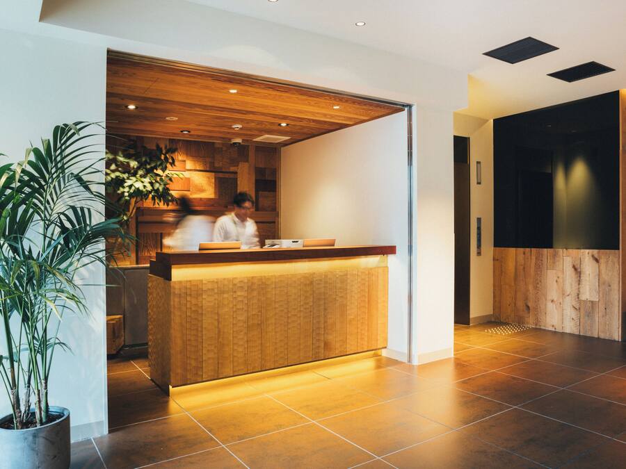 A reception area with a wooden counter, potted plants, and a modern interior design.