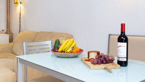 Una mesa de comedor con un bol de fruta, una botella de vino y una tabla de quesos.