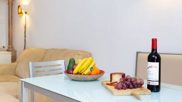 Una mesa de comedor con un bol de fruta, una botella de vino y una tabla de quesos.