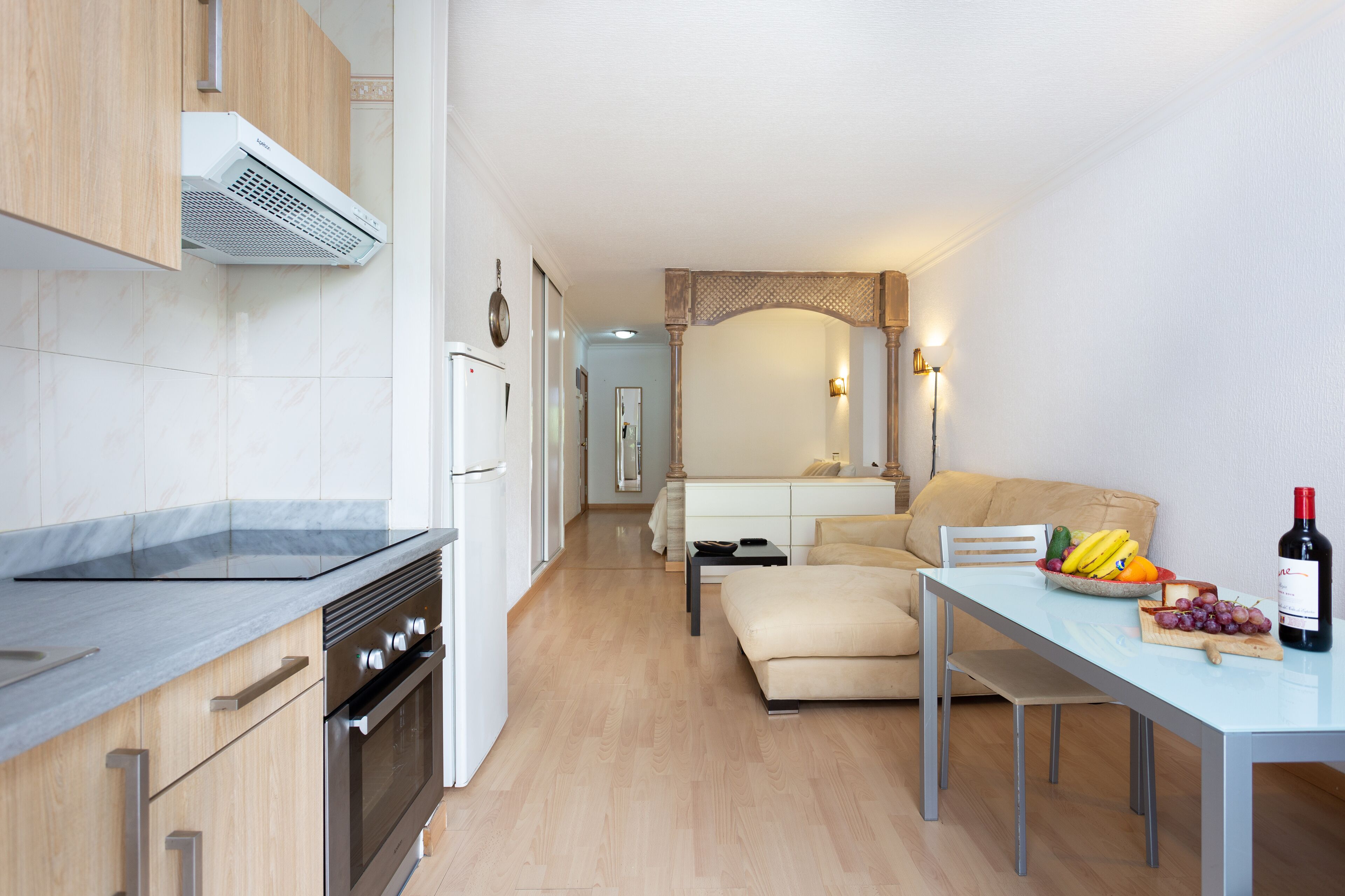 Una cocina moderna con horno empotrado y un comedor con una mesa lista para dos.