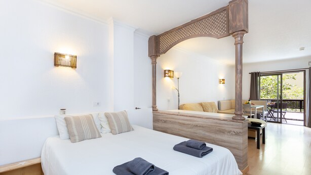 Habitación de hotel con una cama grande, dosel de madera y vistas al exterior.