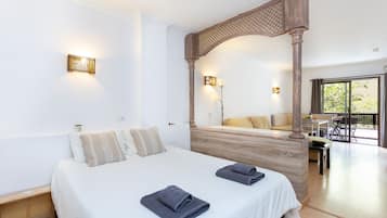 Habitación de hotel con una cama grande, dosel de madera y vistas al exterior.