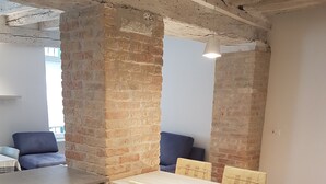 A modern kitchen with a wooden table and chairs, brick walls, and a blue sofa in the background. - Corte Sconta Mini Loft (Venice)