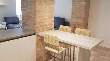 Una cocina moderna con una mesa y sillas de madera, paredes de ladrillo y un sofá azul al fondo.