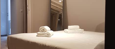 Una habitación de hotel moderna con una cama grande, una mesita de noche y un espejo.