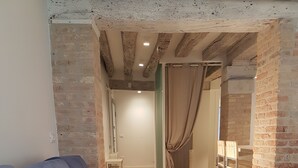 A modern living room with a grey sectional sofa, exposed brick walls, and a wooden floor. - Corte Sconta Mini Loft (Venice)