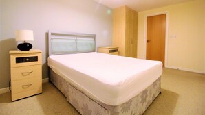 A bedroom with a bed, bedside table, lamp, and a wardrobe. - City Walk (Leeds)