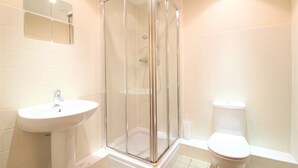 A bathroom with a glass-enclosed shower, a sink, and a toilet. - City Walk (Leeds)