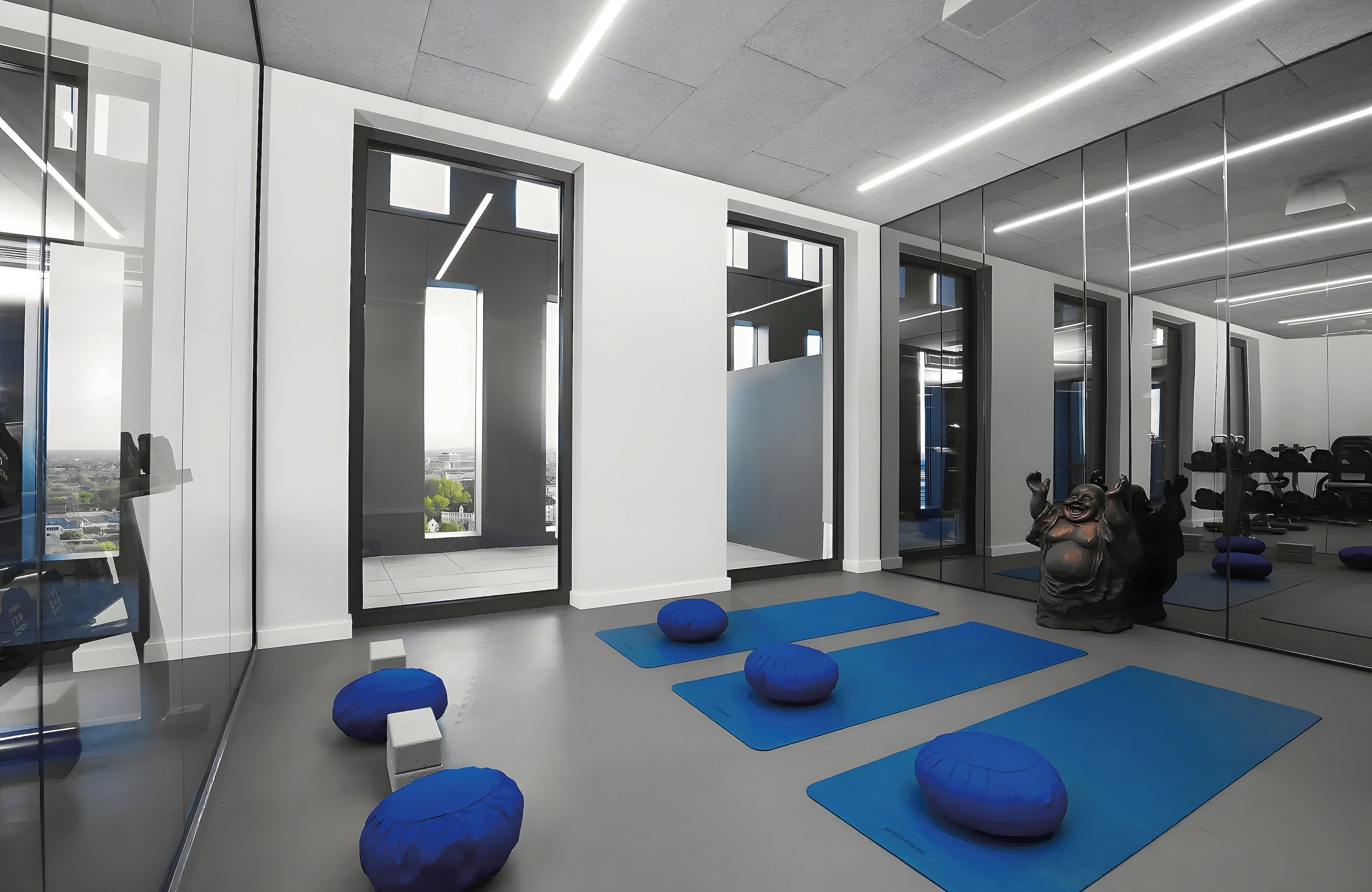 A modern gym with exercise mats, a punching bag, and a view of the city through large windows.