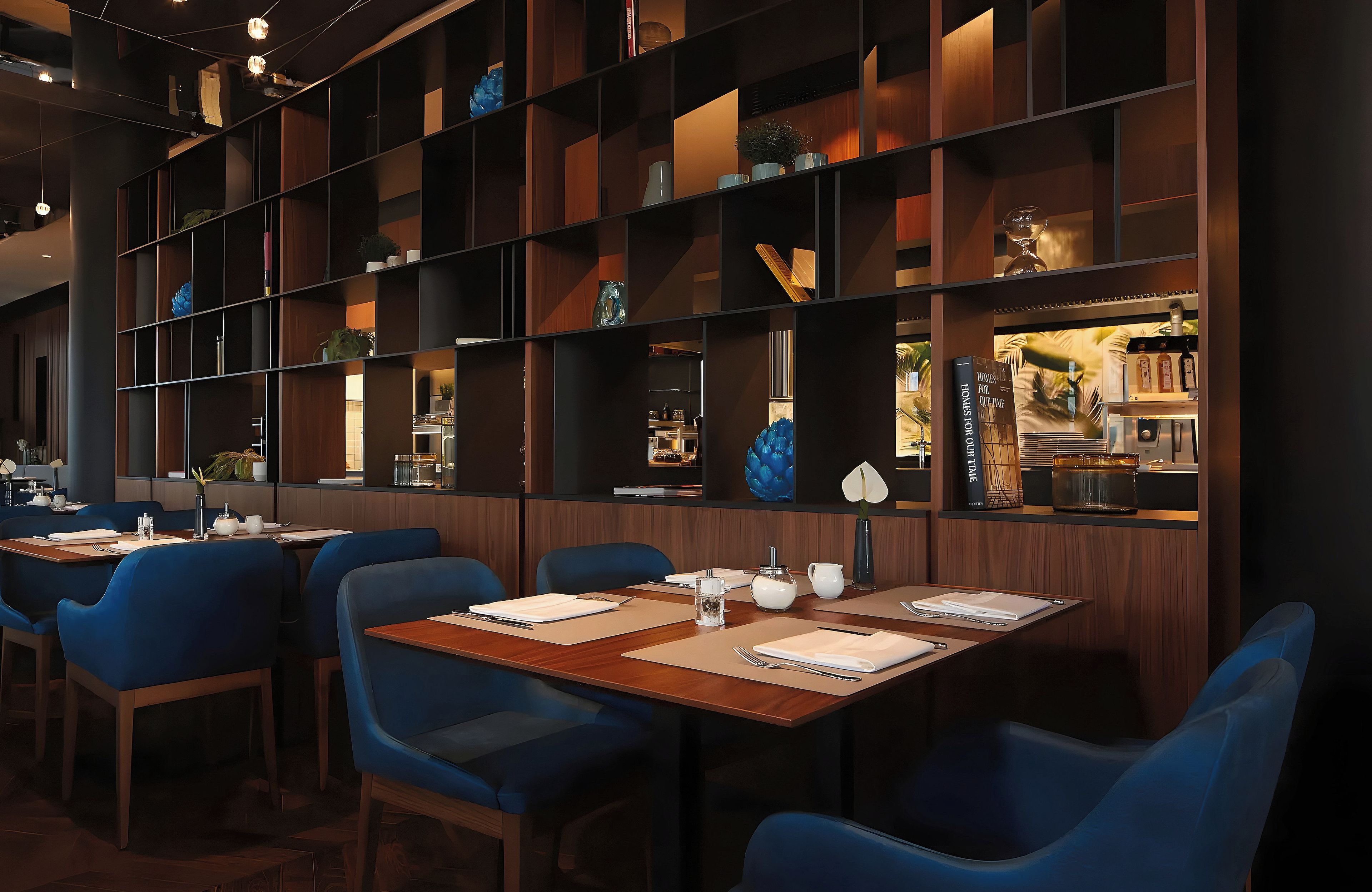 Ein Restaurantinneres mit mehreren Tischen und Stühlen, Holzregalen mit Dekoration und einer Bar mit Flaschen.