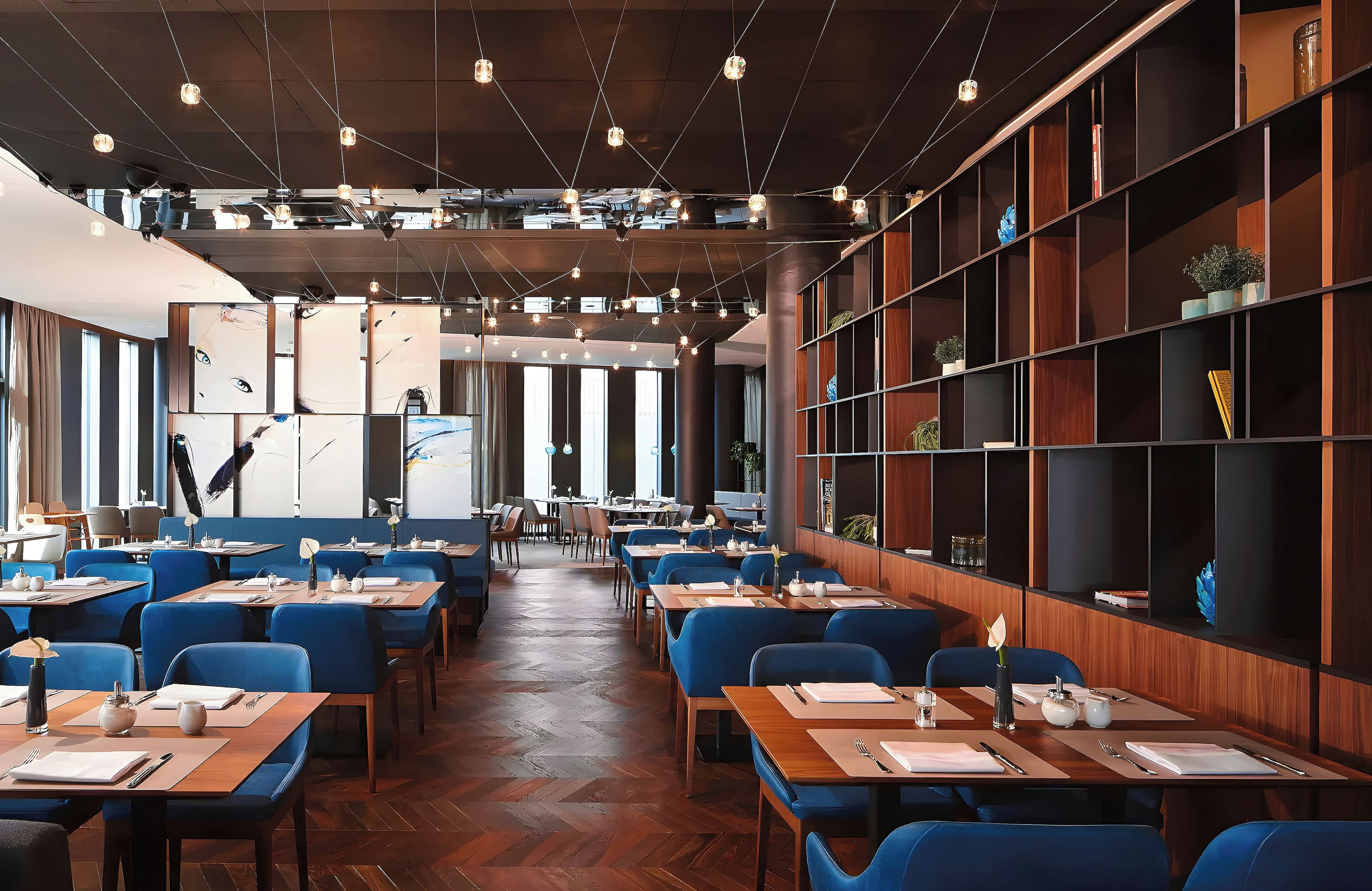 A restaurant with multiple tables and chairs, wooden floors, and a modern interior design.