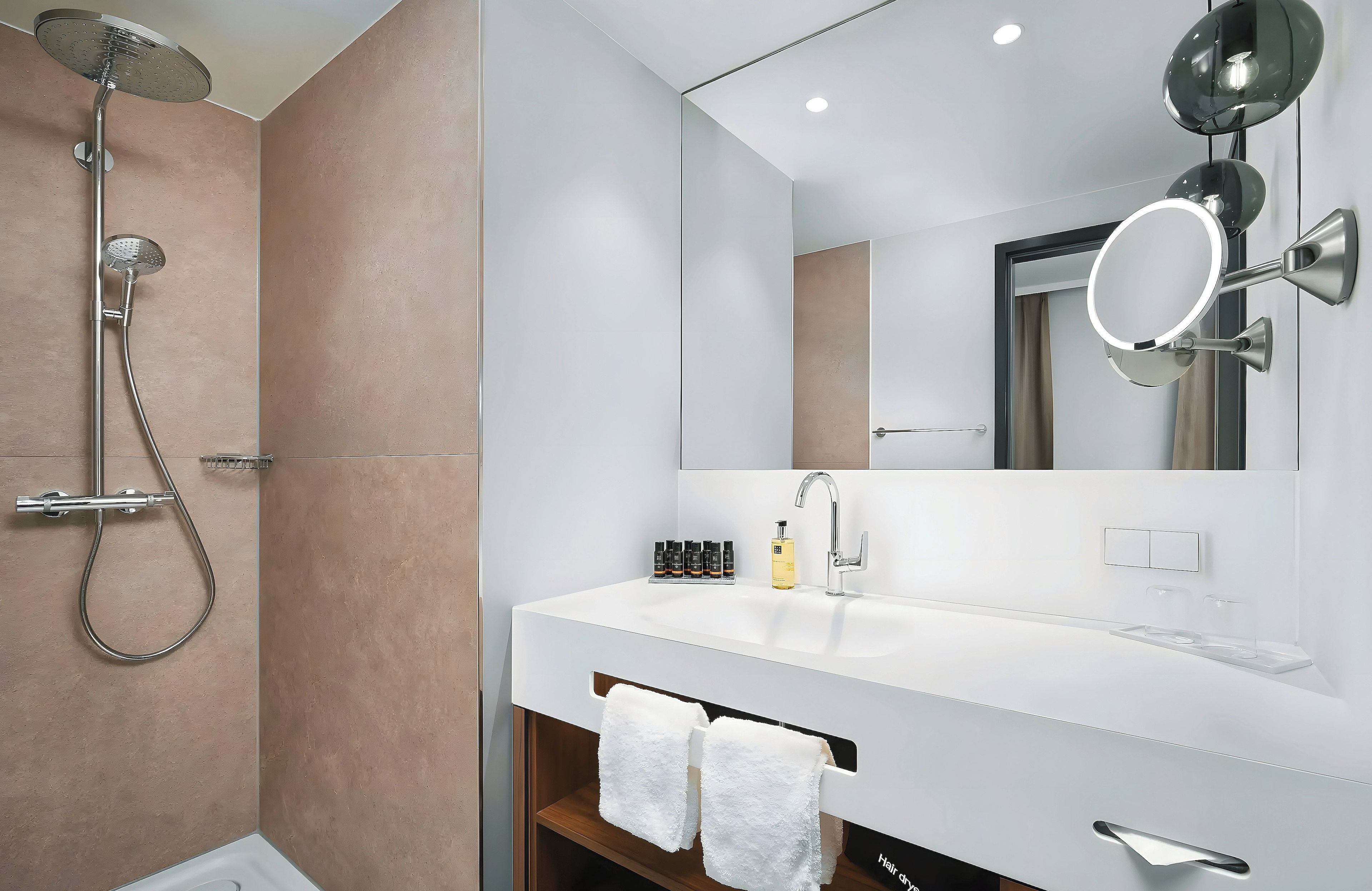 A modern bathroom with a shower, a sink, and a mirror.