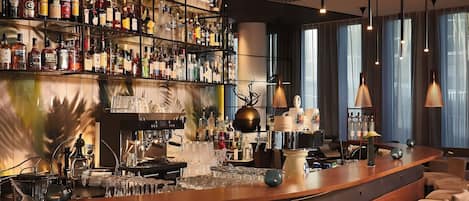 Zona de bar con una variedad de botellas de licor, una máquina de café y asientos.