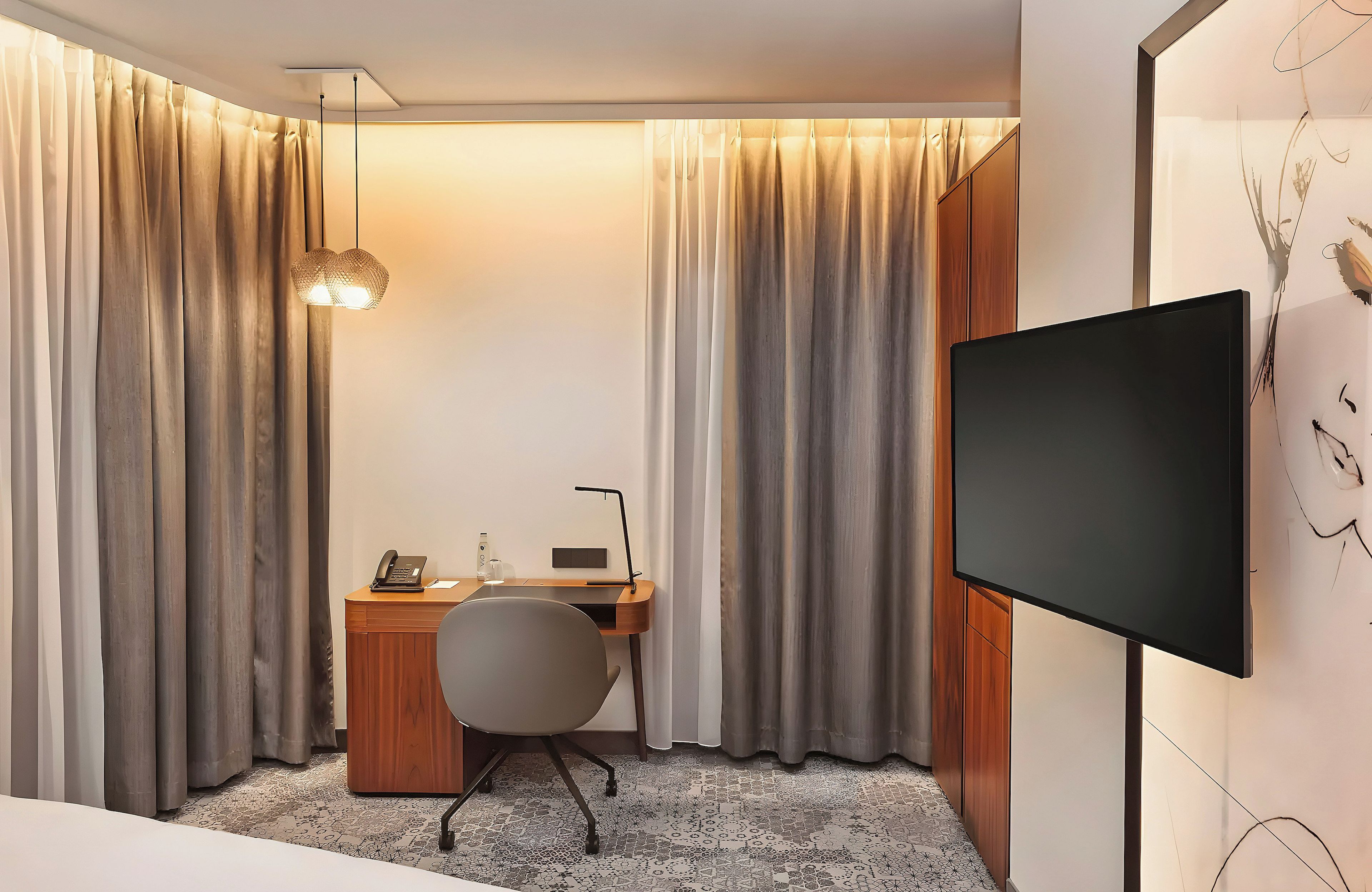 Una habitación de hotel con escritorio, silla y televisor de pantalla plana.
