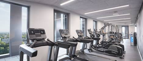 Un gimnasio moderno con cintas de correr, elípticas y equipo de pesas.