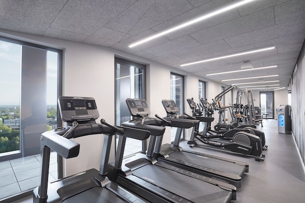 Un gimnasio moderno con cintas de correr, elípticas y equipo de pesas.