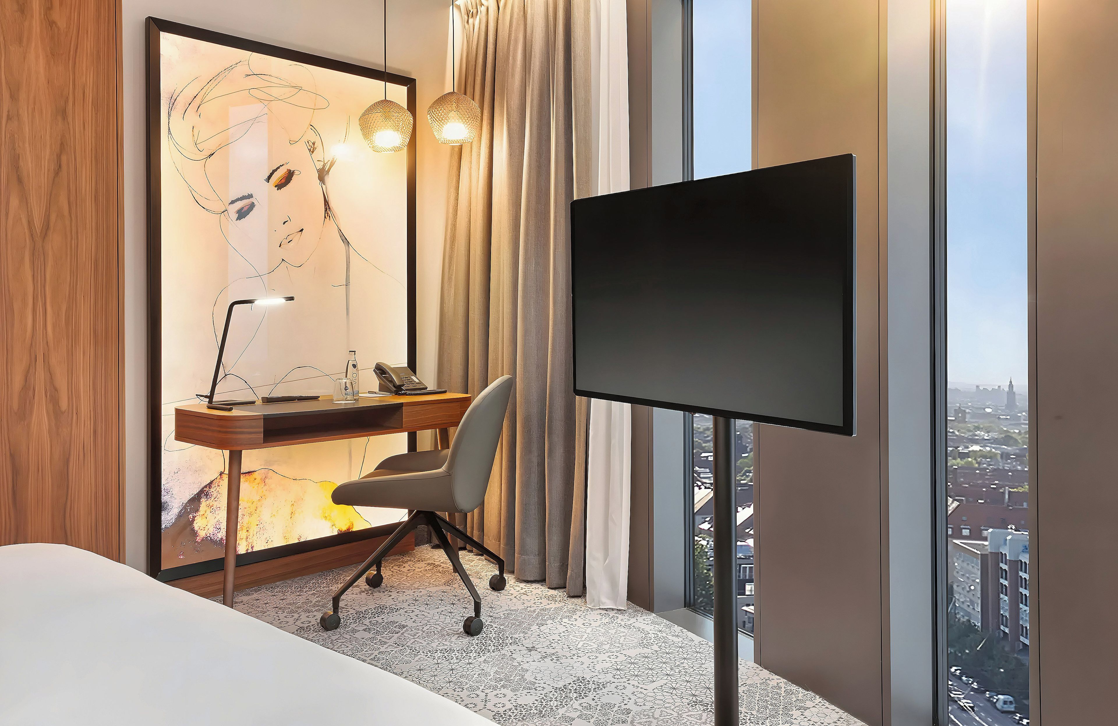 A hotel room with a desk, chair, television, and a large window with a city view.