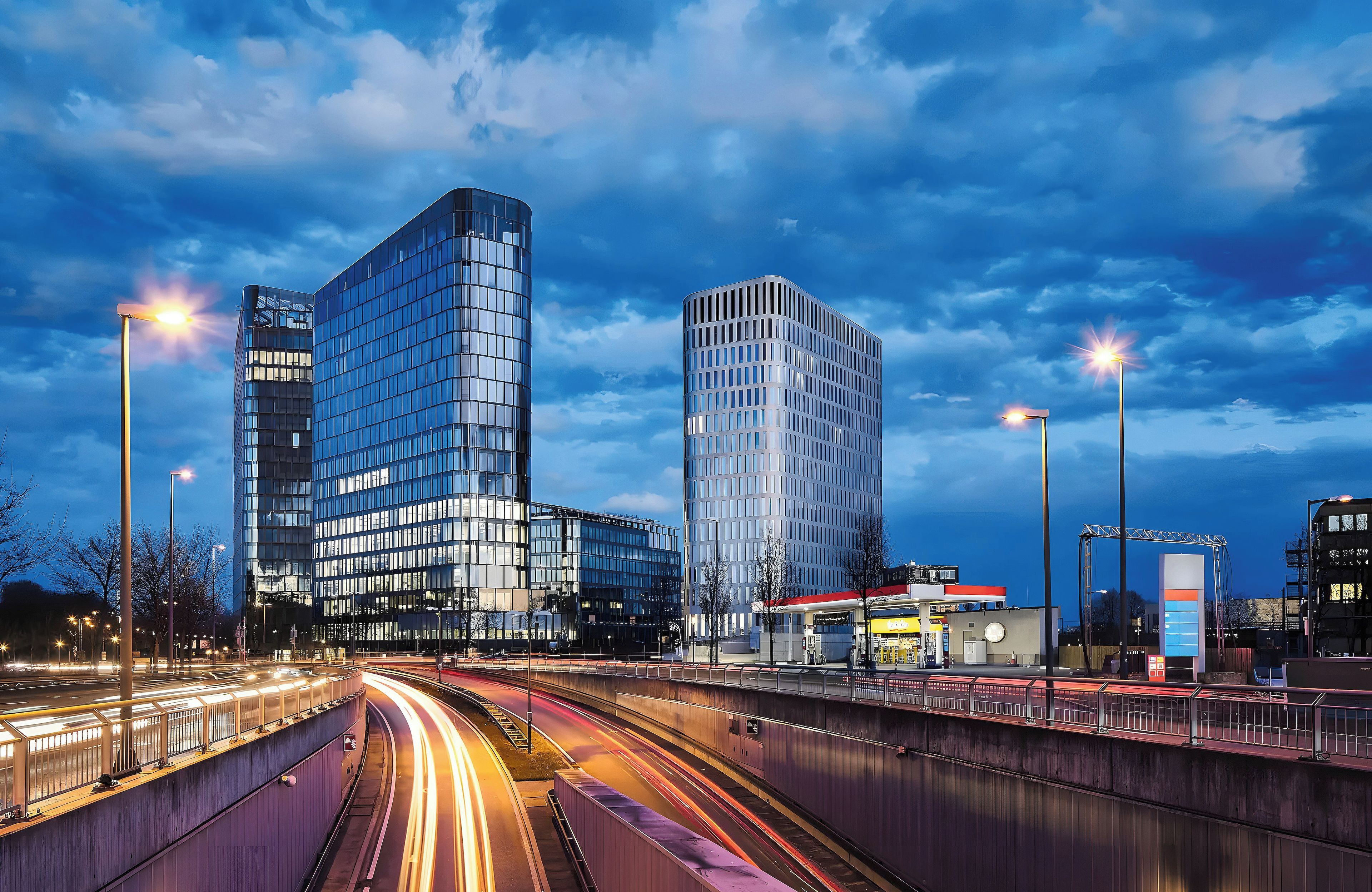 Paesaggio urbano con edifici moderni, un'autostrada e lampioni.