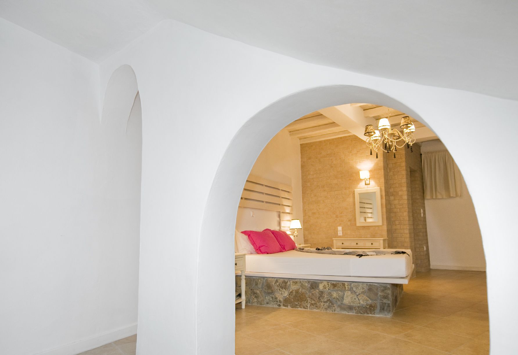 Een slaapkamer met een groot bed, een badkamer met een stenen muur en een kroonluchter.