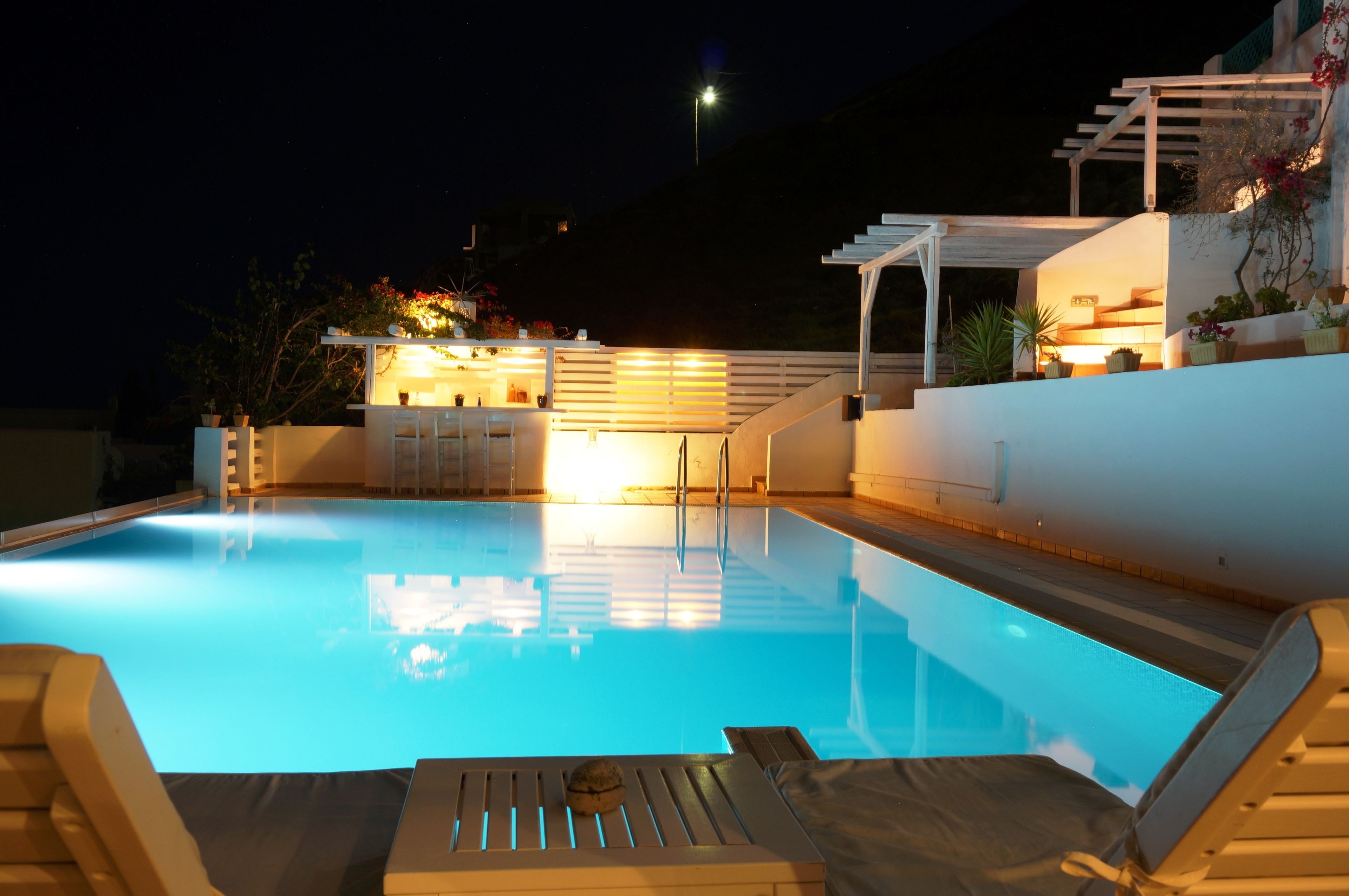 A swimming pool with lounge chairs and a pergola with plants.
