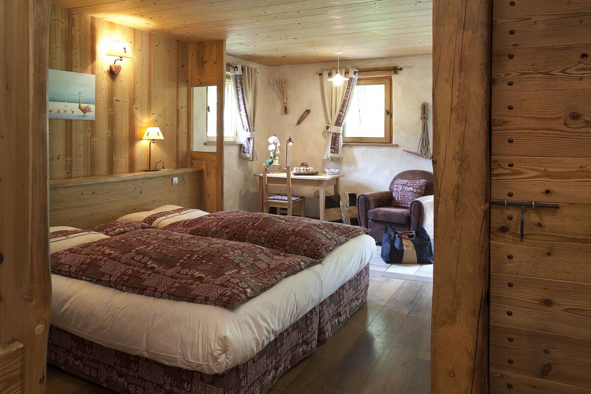 Ein Schlafzimmer einer Holzhütte mit einem großen Bett, einem Schreibtisch und einem Stuhl.